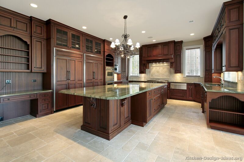 Luxury kitchen with dark cherry cabinets, green granite, travertine floors, a large island, and two refrigerators