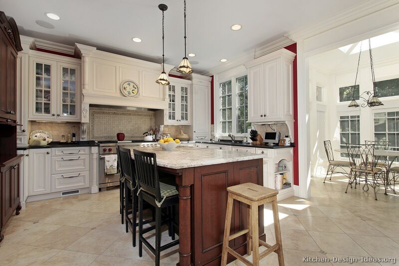 a traditional white kitchen with a dark cherry island